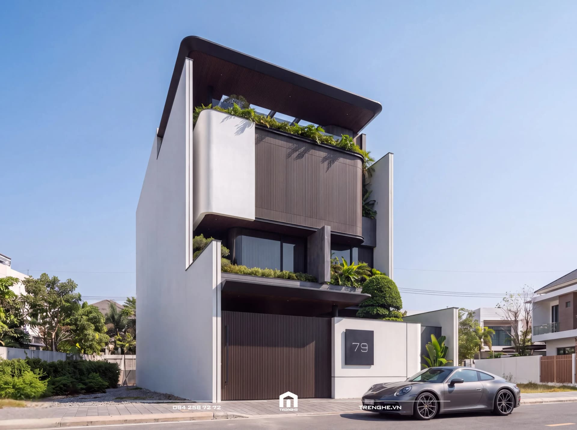 Biệt thự hiện đại nhiệt đới C’ Villa ban ngày nhìn góc trái: tường trắng bo cong hai bên, khối hộp lam gỗ vươn ra, ban công phủ cây xanh, cổng gỗ và tường rào số 79