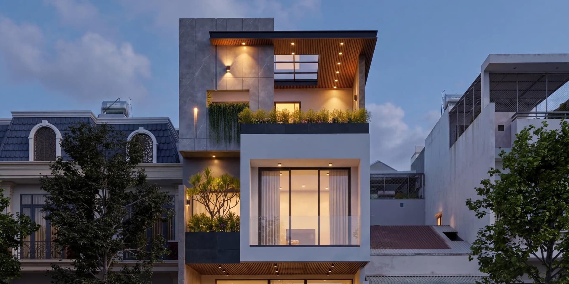 Nhà phố 3 tầng KA’ House lúc chạng vạng, mái bằng ốp lam gỗ và khối hộp trắng sáng đèn giữa dãy phố