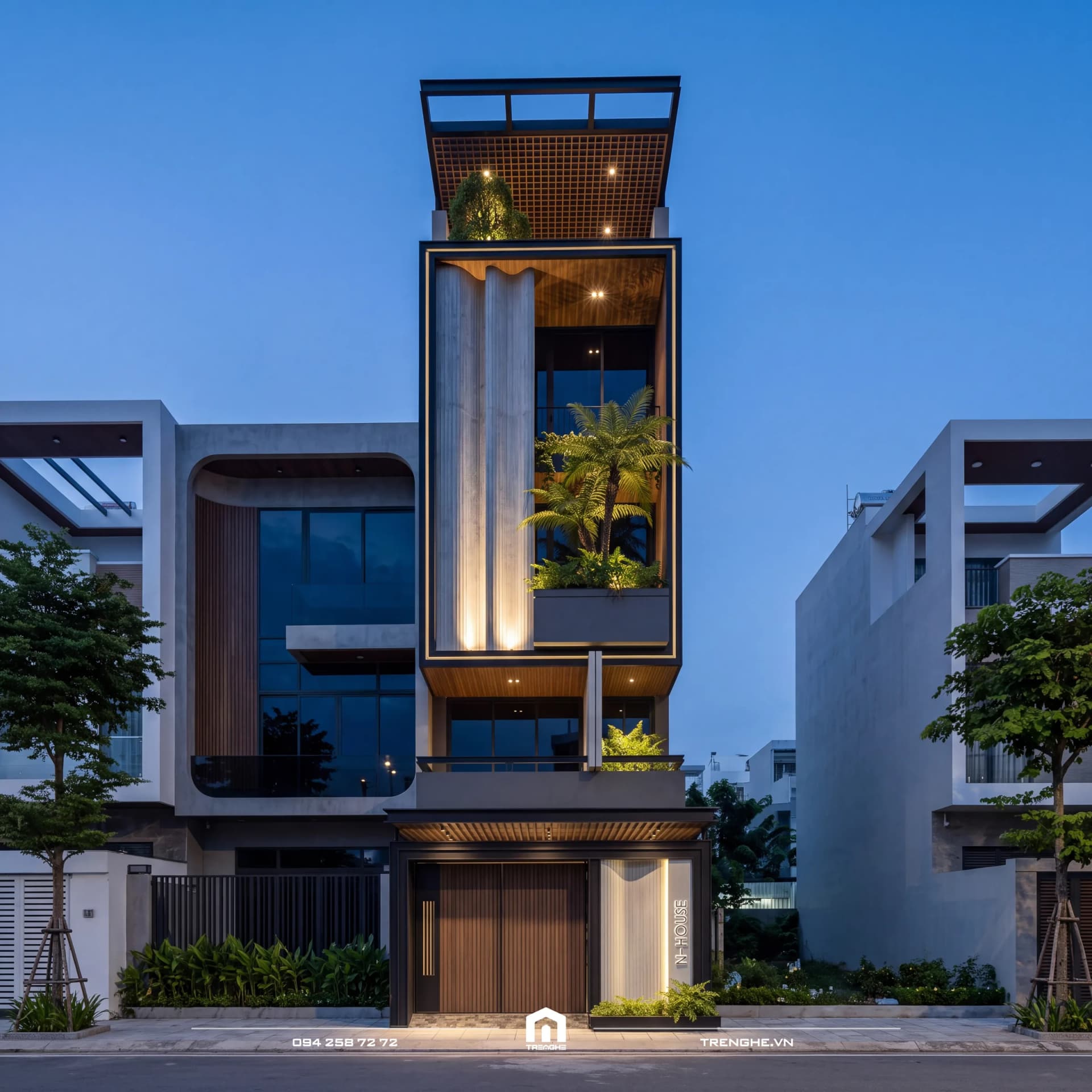 Mặt tiền nhà phố N’ House lúc chạng vạng giữa dãy phố: khung đen ôm ban công trồng cau, tấm lam trắng dạng sóng, giàn lam sân thượng và cửa gỗ tầng trệt