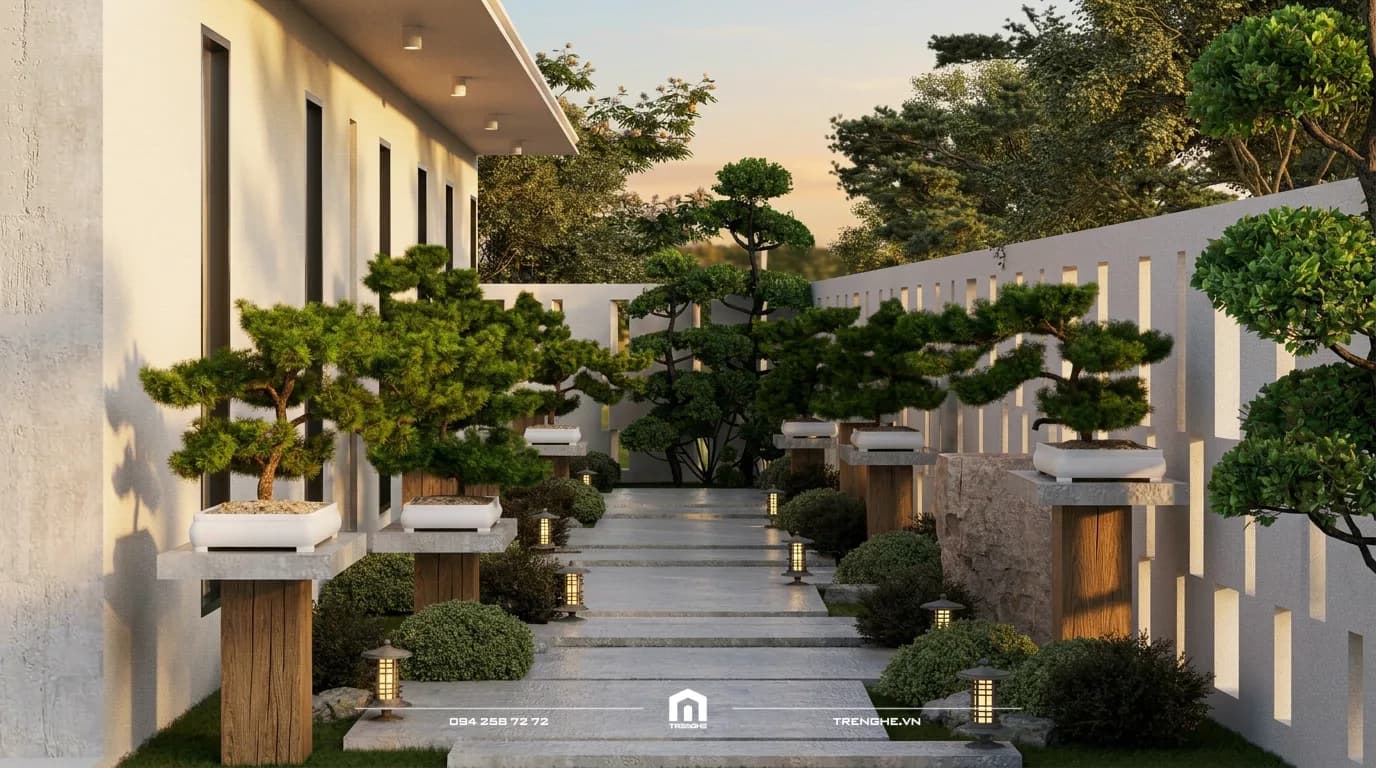 Lối đi bên hông nhà vườn N’ Villa với hàng chậu bonsai trên trụ gỗ và đèn sân vườn lúc chiều tà