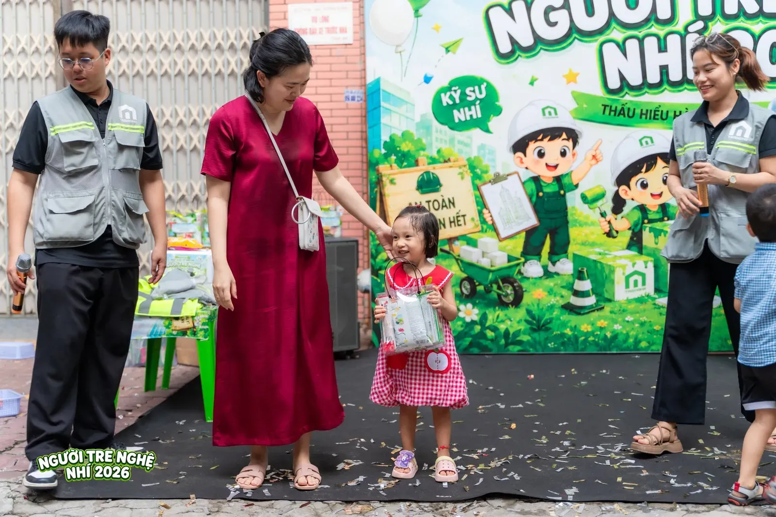 Niềm vui nhỏ xinh của bé khi được nhận phần quà ý nghĩa từ Ban Tổ Chức trong sự đồng hành và nụ cười ấm áp của mẹ.